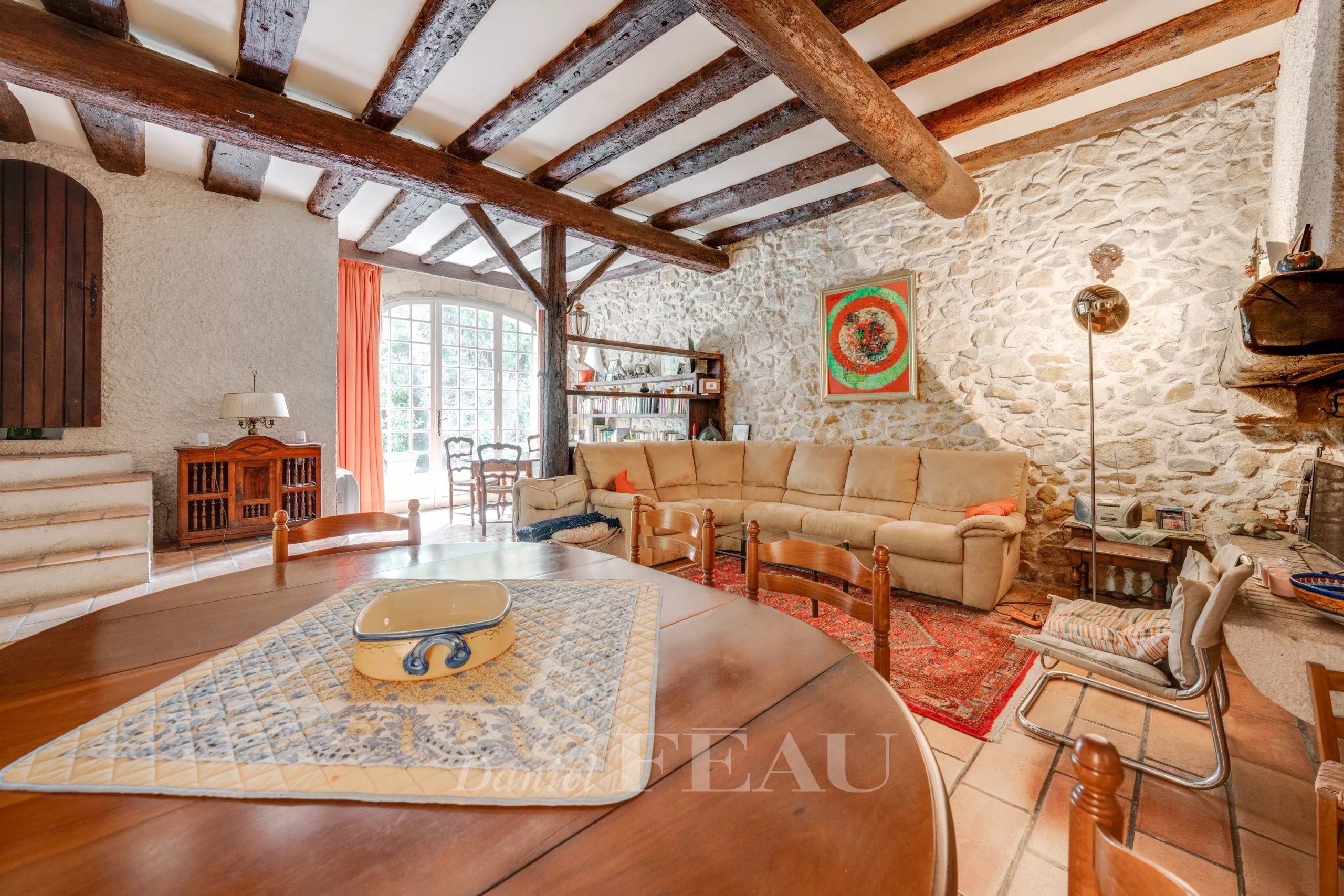 Intérieur d'un mas à rénover avec un salon spacieux et des poutres apparentes.