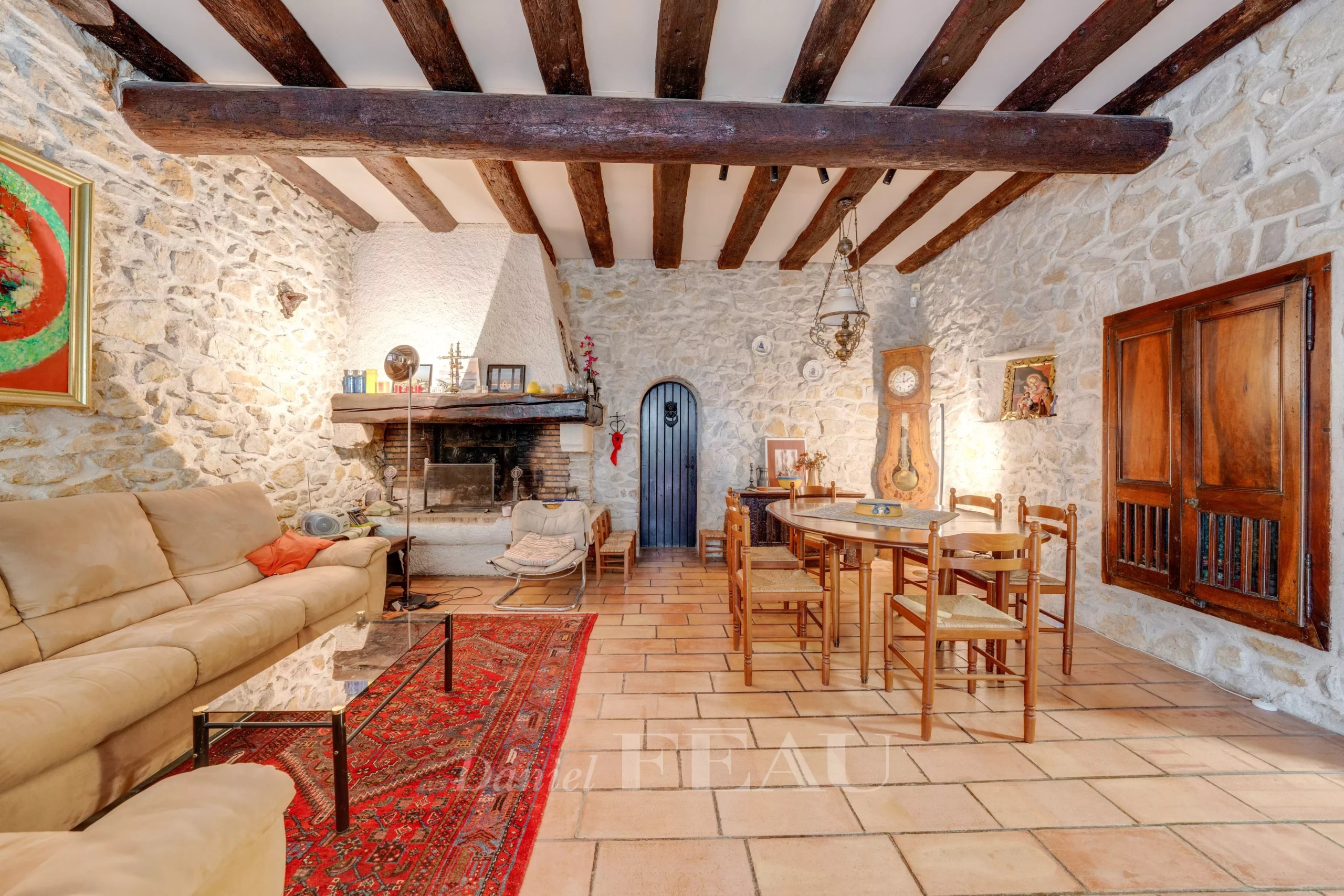 Intérieur d'un mas en pierre avec cheminée, salon et salle à manger, décor rustique.