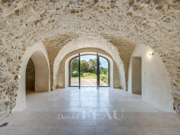 Intérieur d'un mas du XVIIIe siècle rénové avec plafonds voûtés en pierre et grandes baies vitrées.