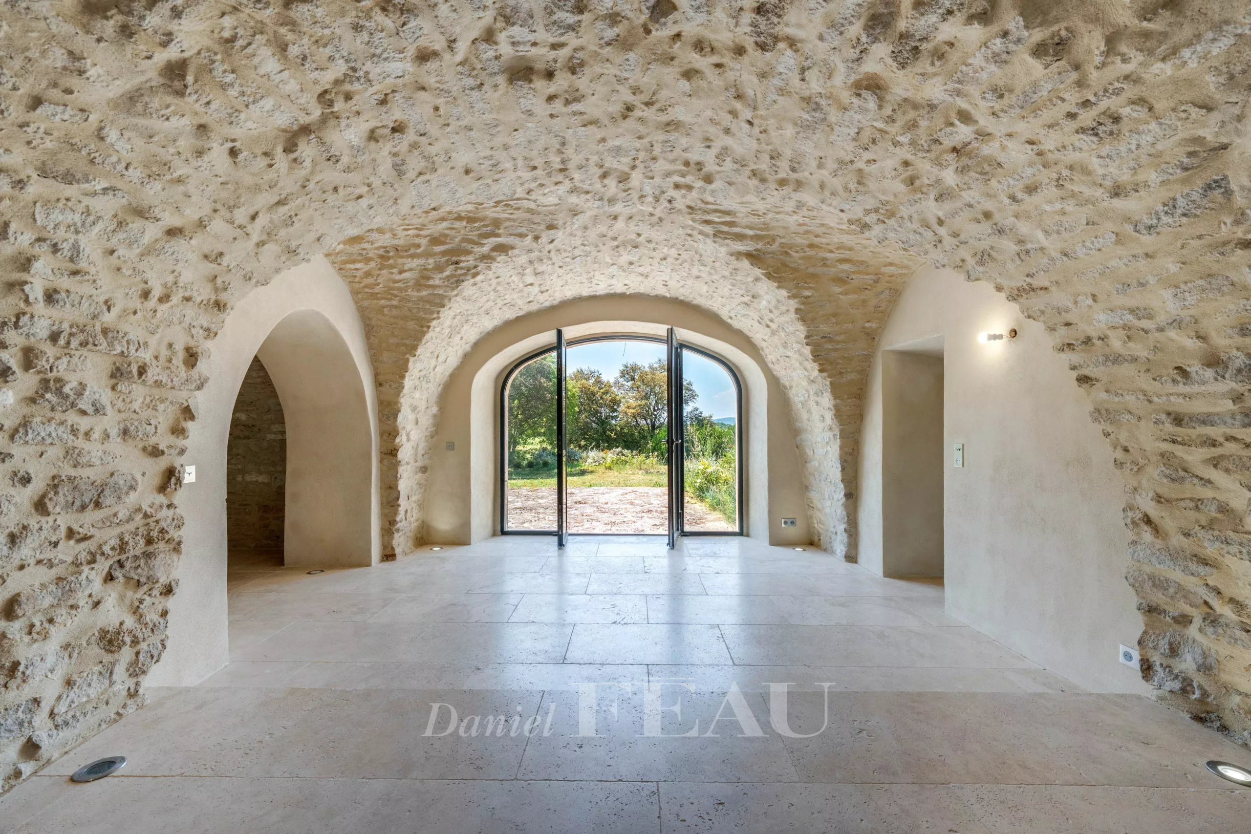 Intérieur d'un mas du XVIIIe siècle rénové avec plafonds voûtés en pierre et grandes baies vitrées.