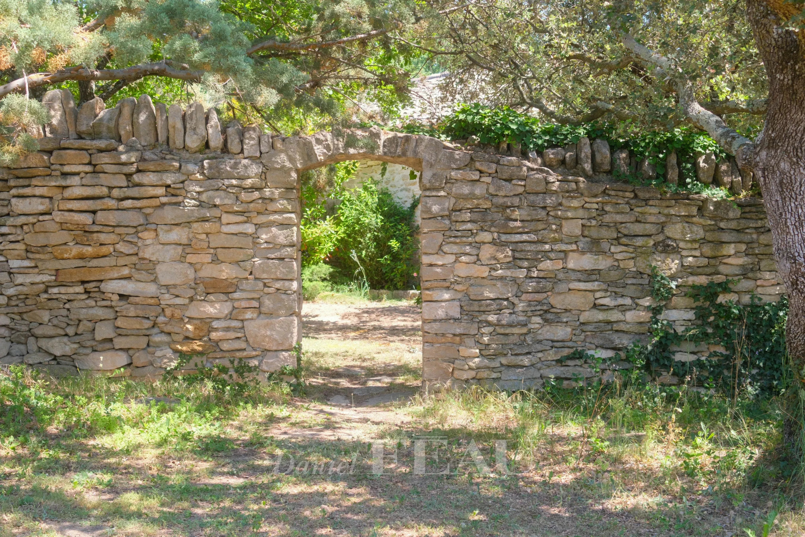 Portail en pierre dans un parc verdoyant à Ménerbes
