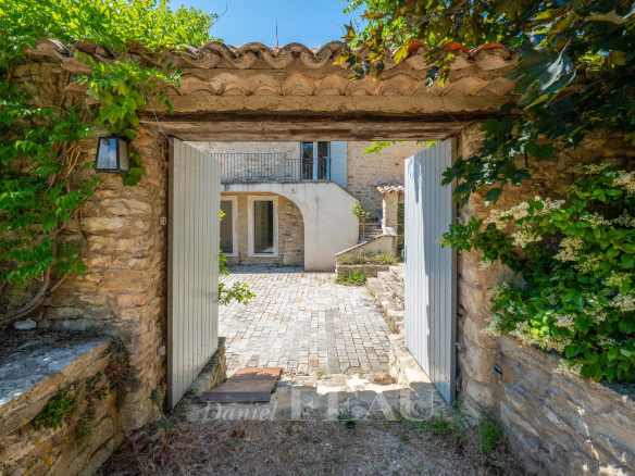 Entrée d'un mas du XVIIIe siècle rénové à Ménerbes avec cour intérieure en pierre.
