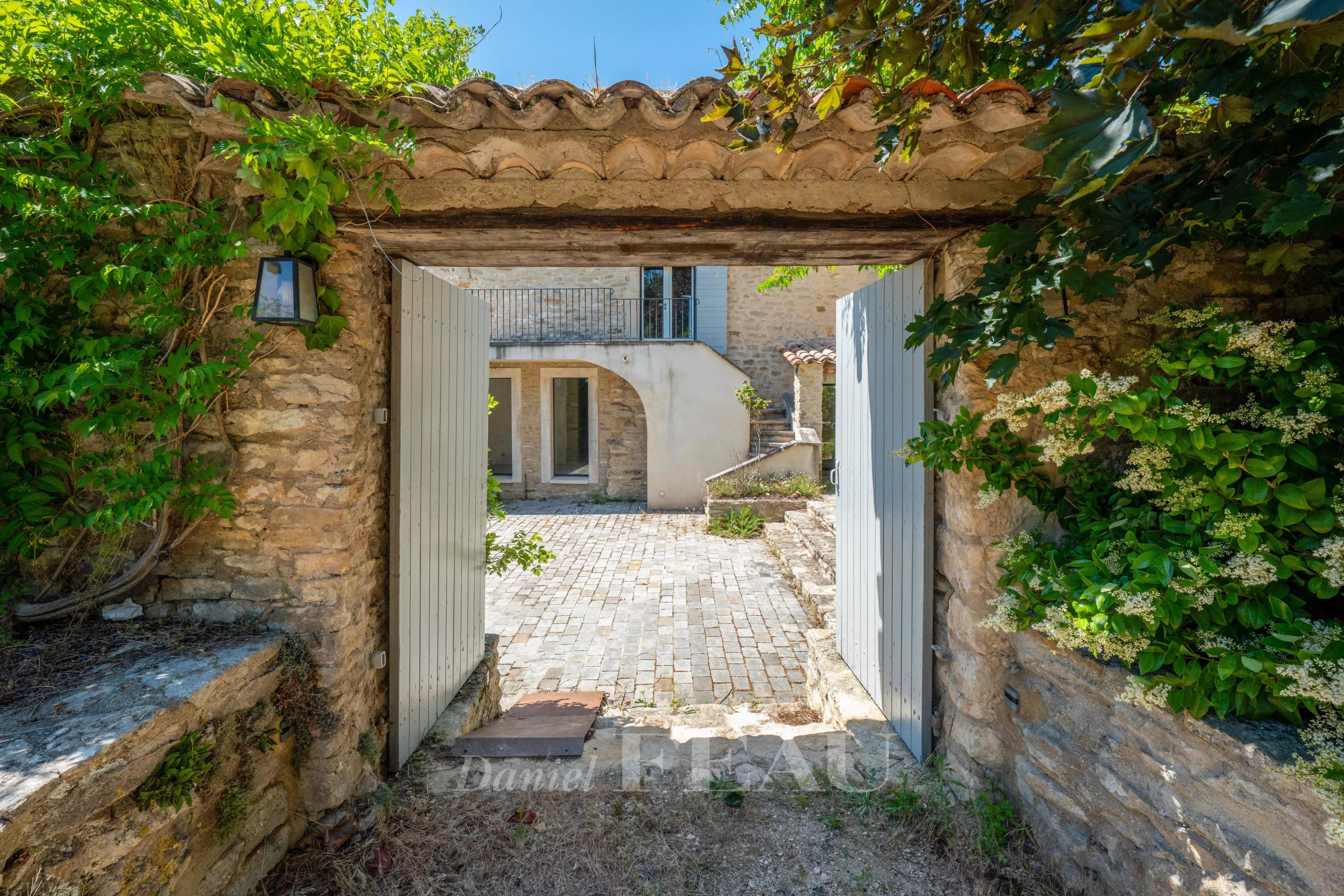 Entrée d'un mas du XVIIIe siècle rénové à Ménerbes avec cour intérieure en pierre.