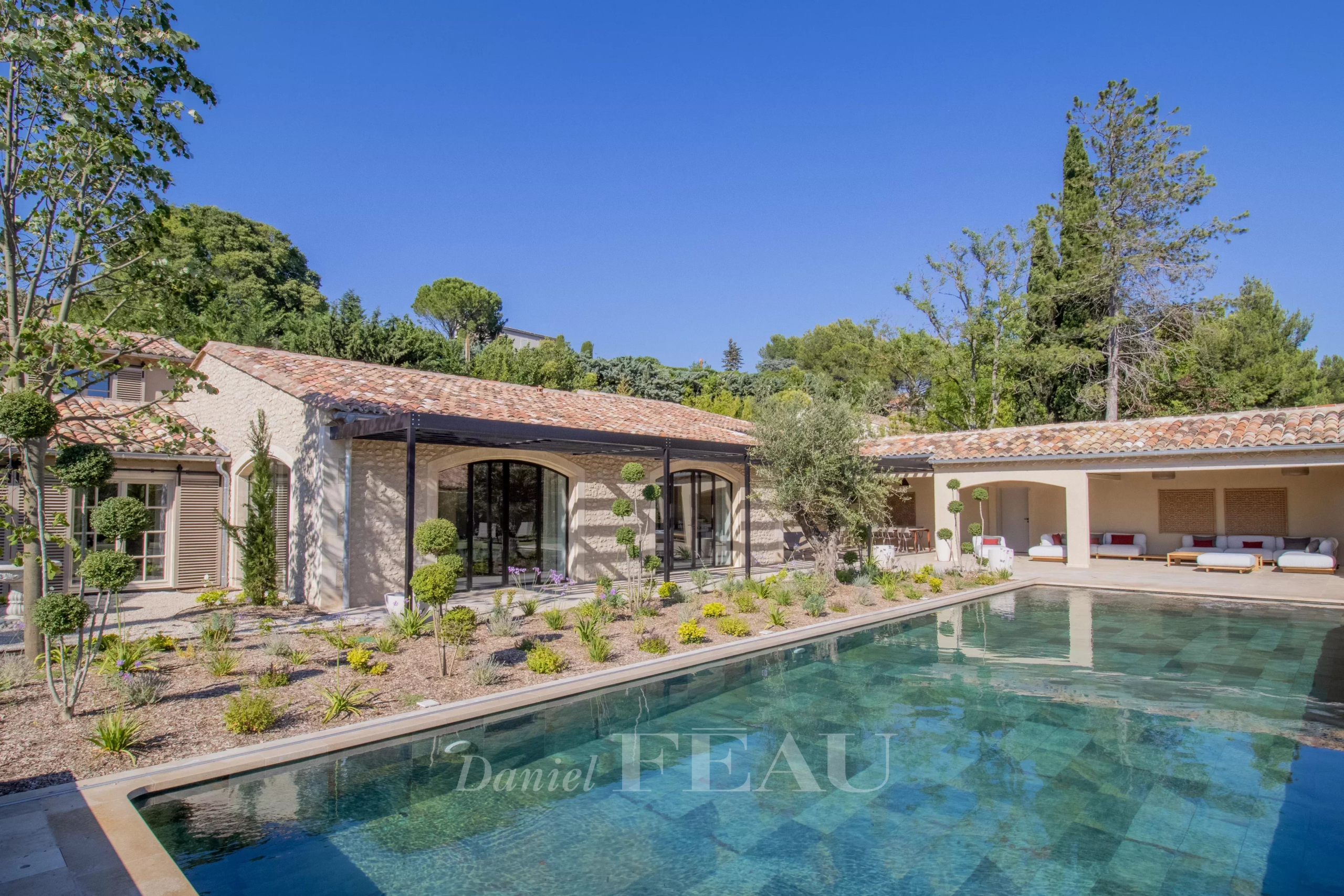 Renovated stone house with swimming pool in Maussane-les-Alpilles, surrounded by greenery.