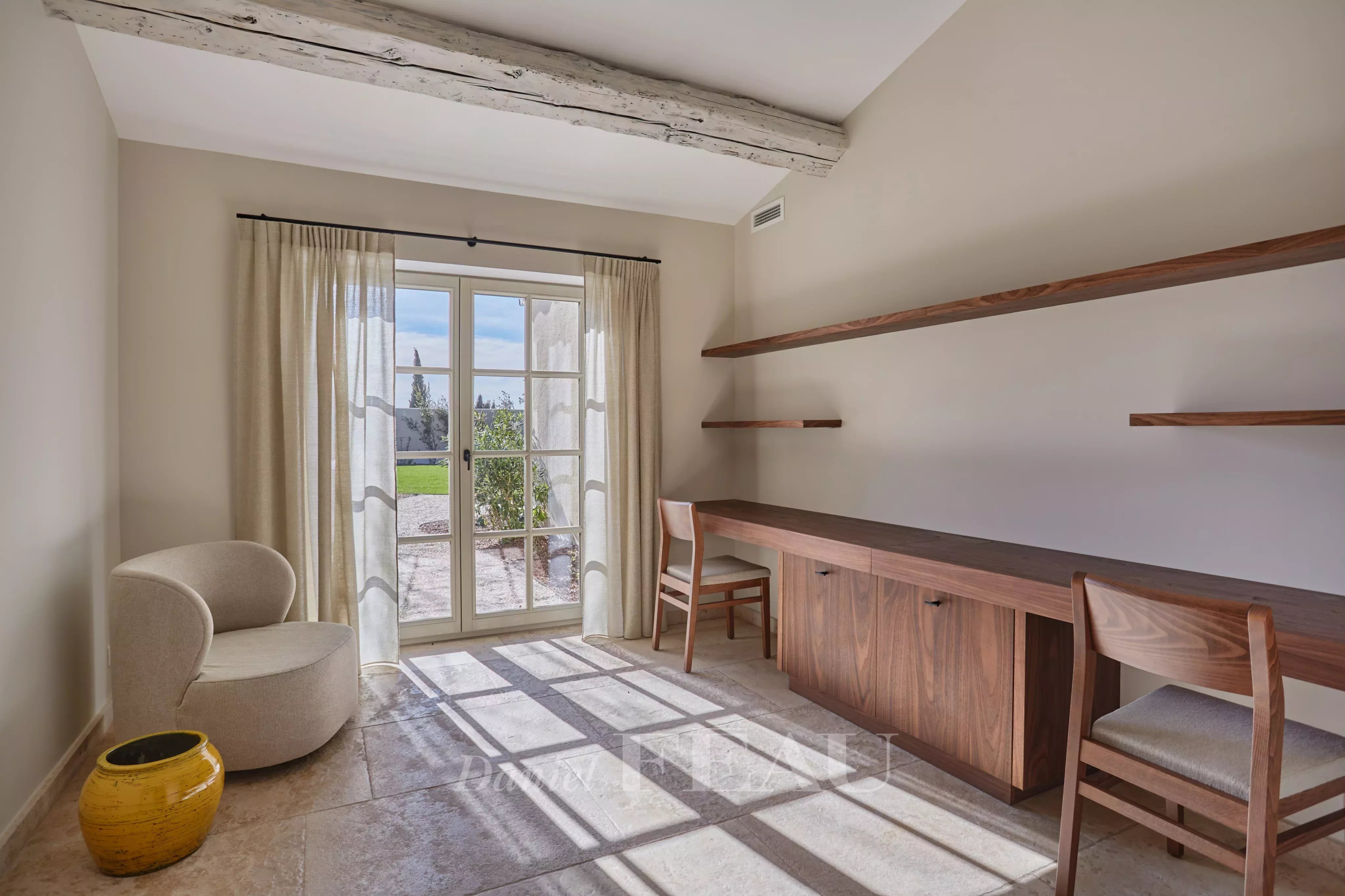Interior of a renovated stone house with an office and a view of the garden.