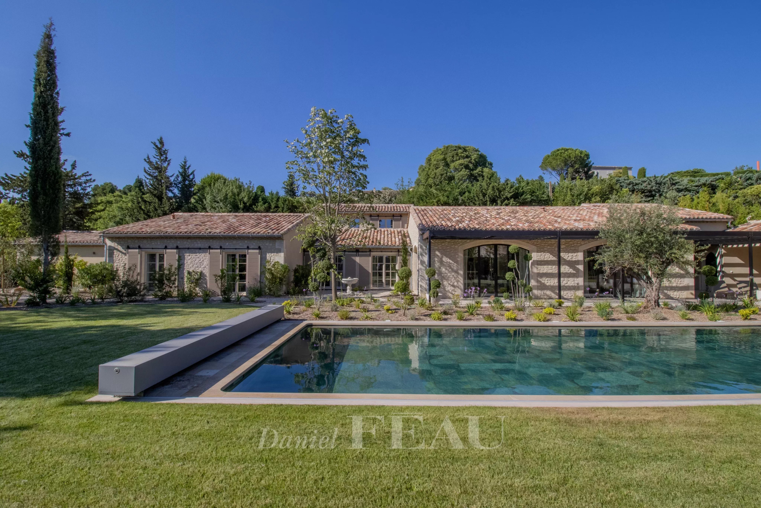 Renovated stone house with swimming pool in Maussane-les-Alpilles, surrounded by greenery.