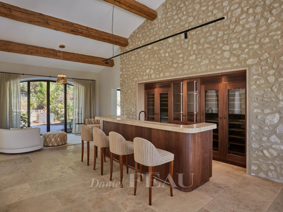 Interior of a renovated stone house with a bar and exposed beams.