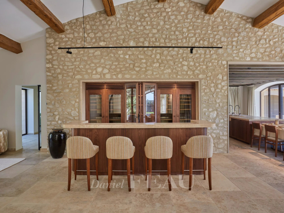 Interior of a renovated stone house with a bar and bright living space in Maussane-les-Alpilles.