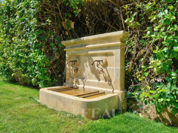 Fontaine en pierre dans un jardin paysager avec des plantes méditerranéennes