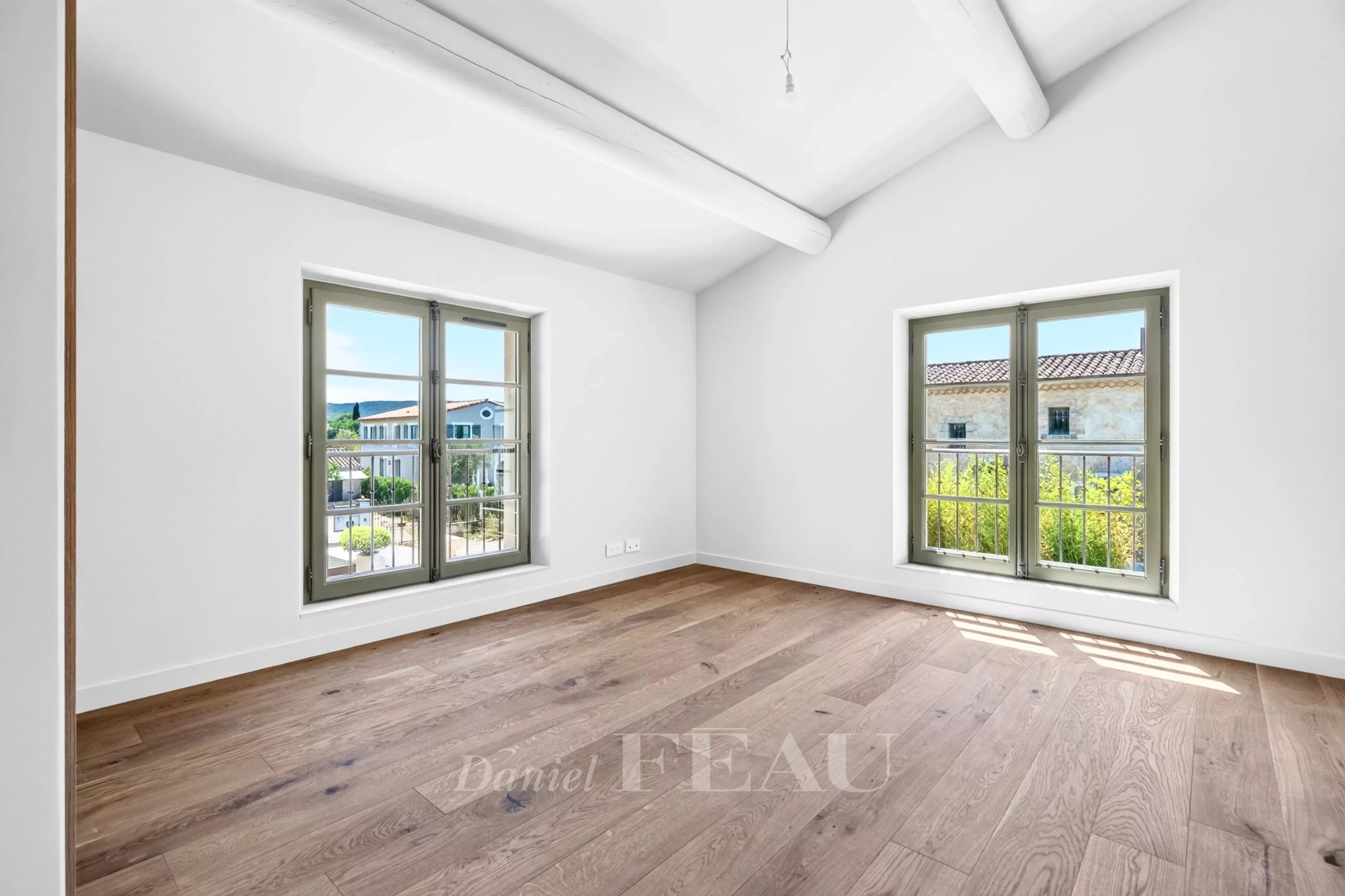 Intérieur d'une maison contemporaine à Eygalières avec deux fenêtres et un sol en bois.