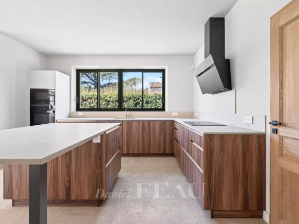 Cuisine moderne avec îlot central et fenêtres donnant sur un jardin, maison contemporaine à Eygalières.