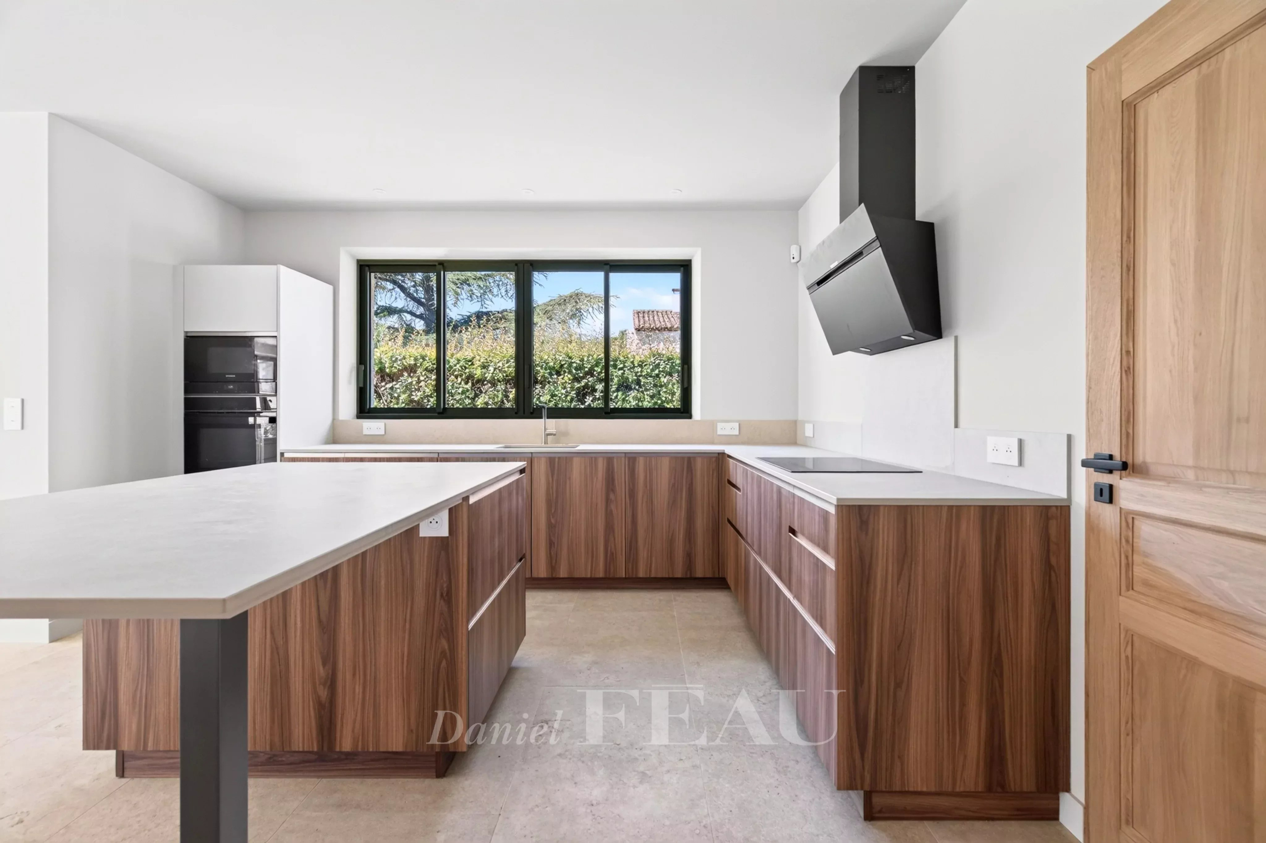Cuisine moderne avec îlot central et fenêtres donnant sur un jardin, maison contemporaine à Eygalières.