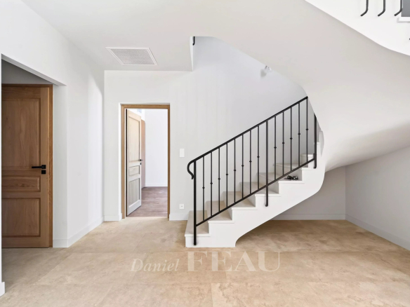 Intérieur d'une maison contemporaine avec un escalier moderne et des murs clairs.