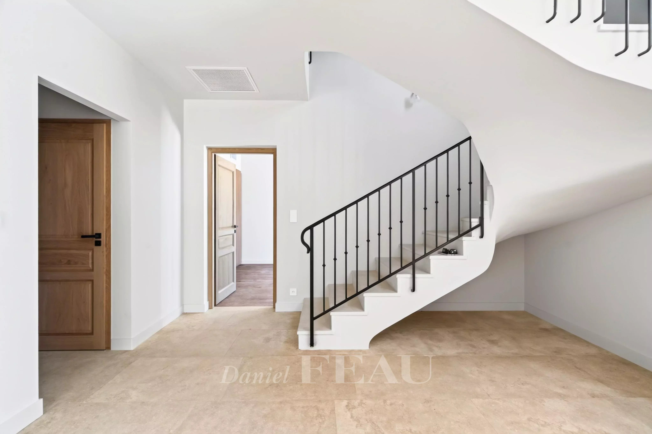 Intérieur d'une maison contemporaine avec un escalier moderne et des murs clairs.