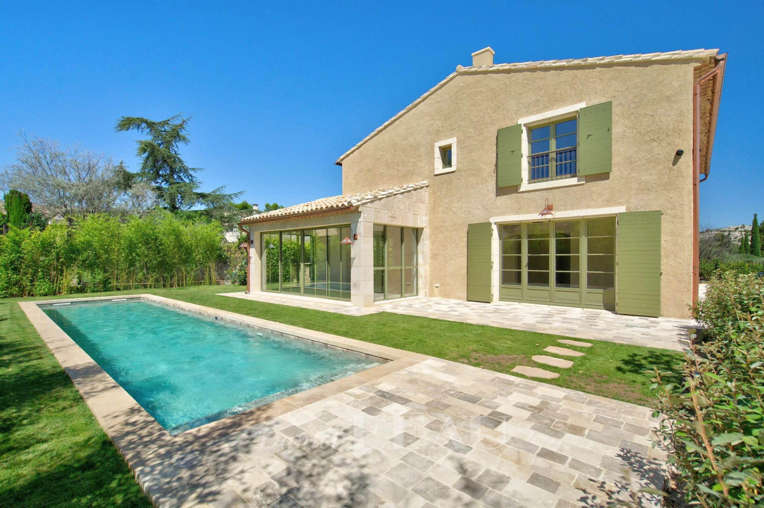 Maison contemporaine avec piscine à Eygalières, jardin paysager et façade en pierre.