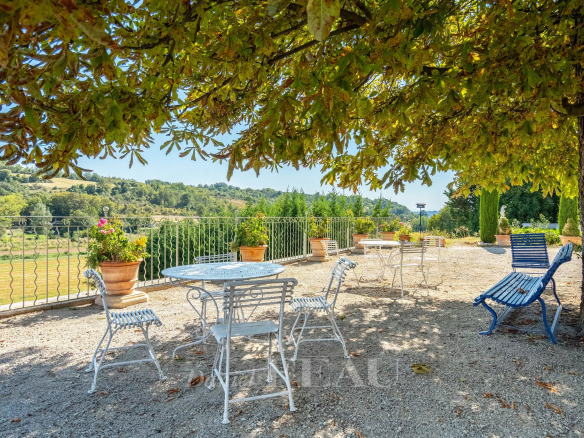 Terrasse ensoleillée avec chaises et tables en métal, vue sur la nature à Valensole.