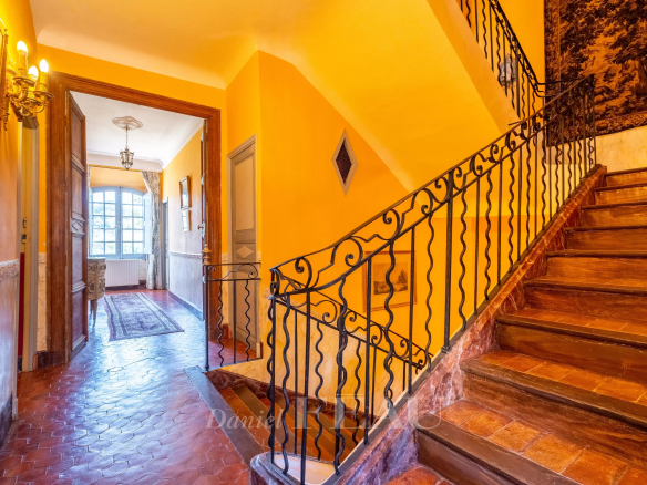 Intérieur d'un château du XVIIème siècle avec un escalier en fer forgé et des murs colorés.