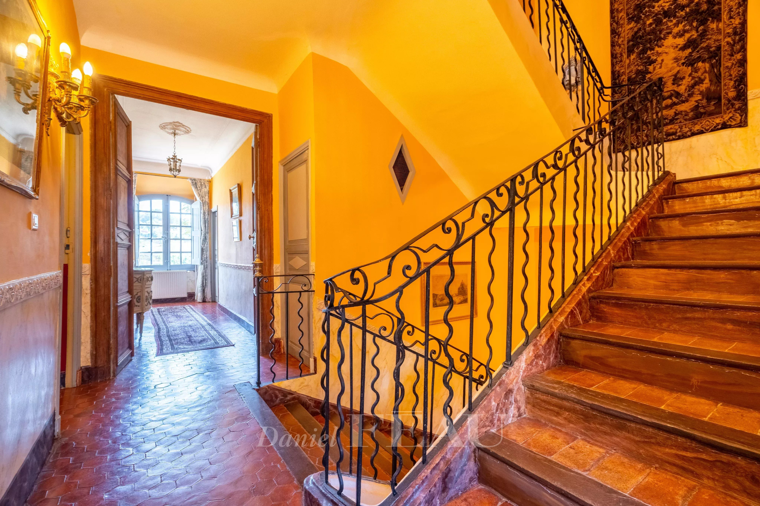 Intérieur du Château de Valensole Intérieur d'un château du XVIIème siècle avec un escalier en fer forgé et des murs colorés.