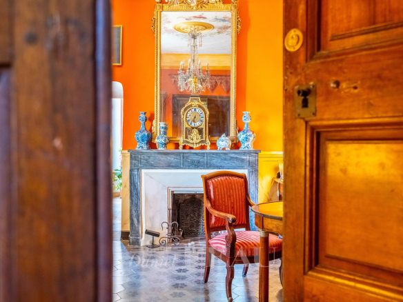 Intérieur d'un château du XVIIème siècle avec cheminée, miroir et mobilier ancien.