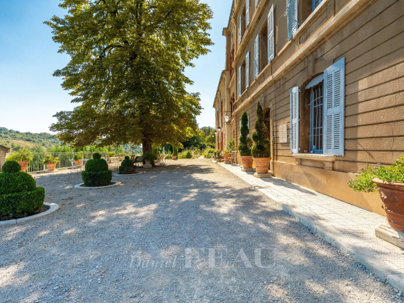 Vue du château du XVIIème siècle à Valensole, avec des jardinières et un chemin gravillonné.