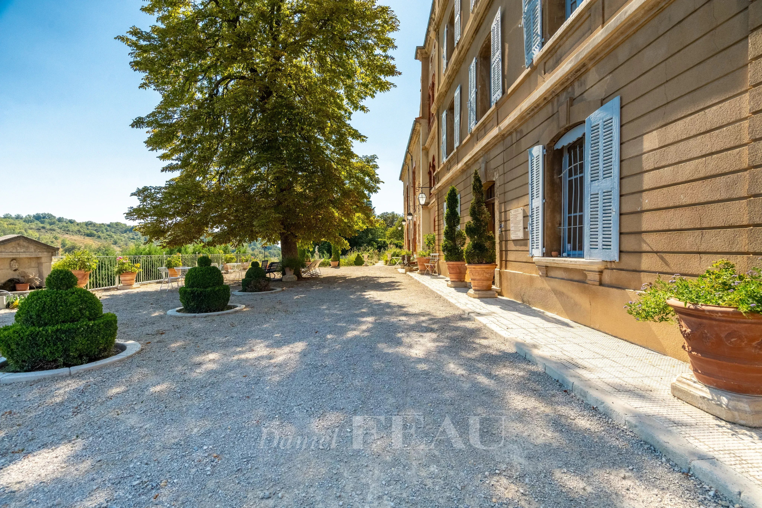 Château du XVIIème siècle à Valensole Vue du château du XVIIème siècle à Valensole, avec des jardinières et un chemin gravillonné.