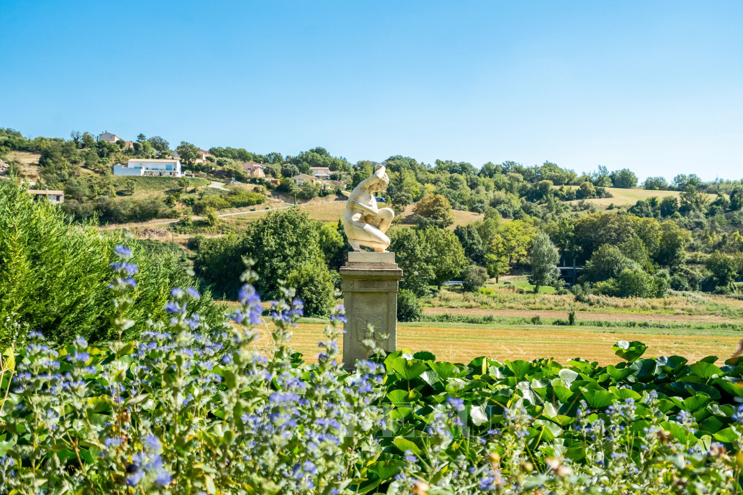 Paysage de Valensole avec sculpture Vue d'un paysage avec une sculpture sur un socle, entourée de fleurs et de verdure à Valensole.