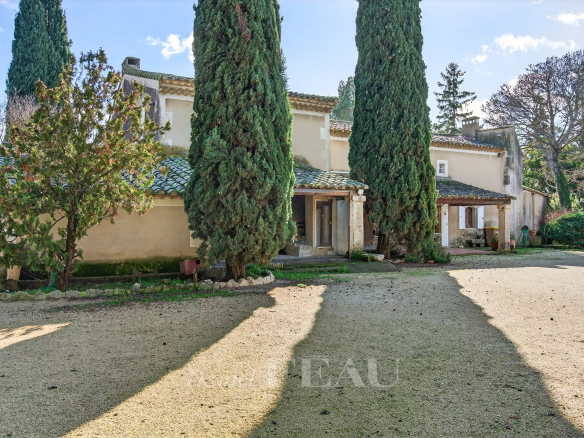 Provençal farmhouse restored in 1985, located in Cavaillon, surrounded by cypress trees and a wooded park.