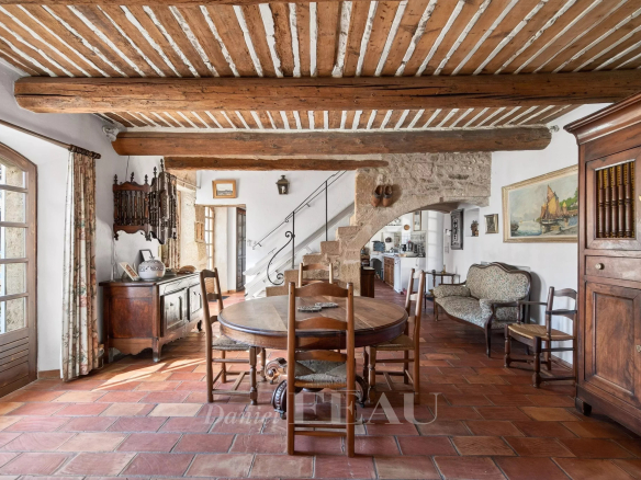 Interior of a Provençal farmhouse with a wooden dining room and exposed beams.