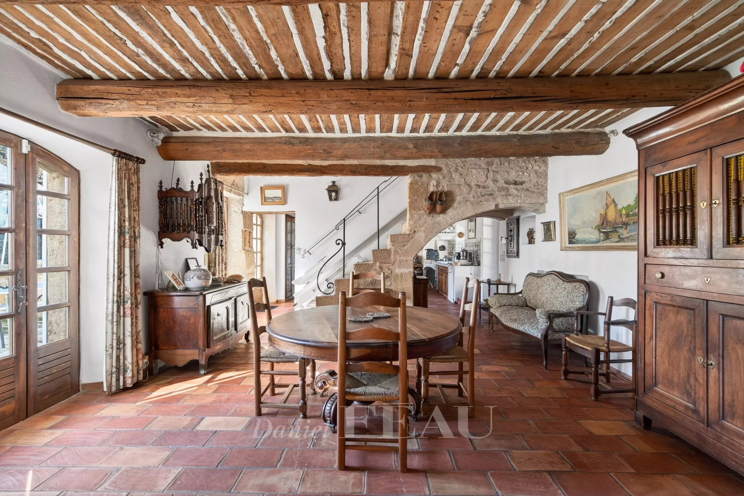 Interior of a Provençal farmhouse with a wooden dining room and exposed beams.