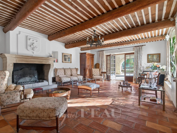 Interior of a Provençal farmhouse with fireplace, antique furniture and exposed beams.