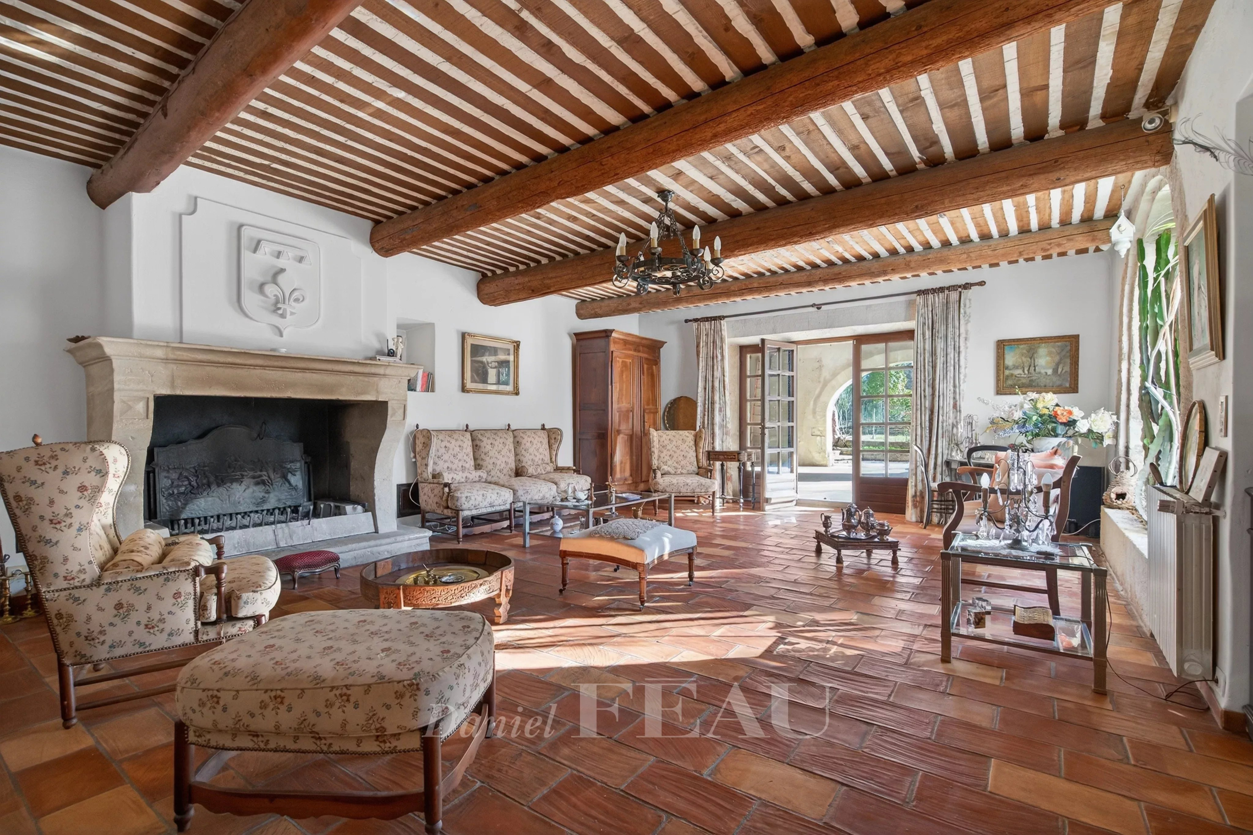 Interior of a Provençal farmhouse with fireplace, antique furniture and exposed beams.