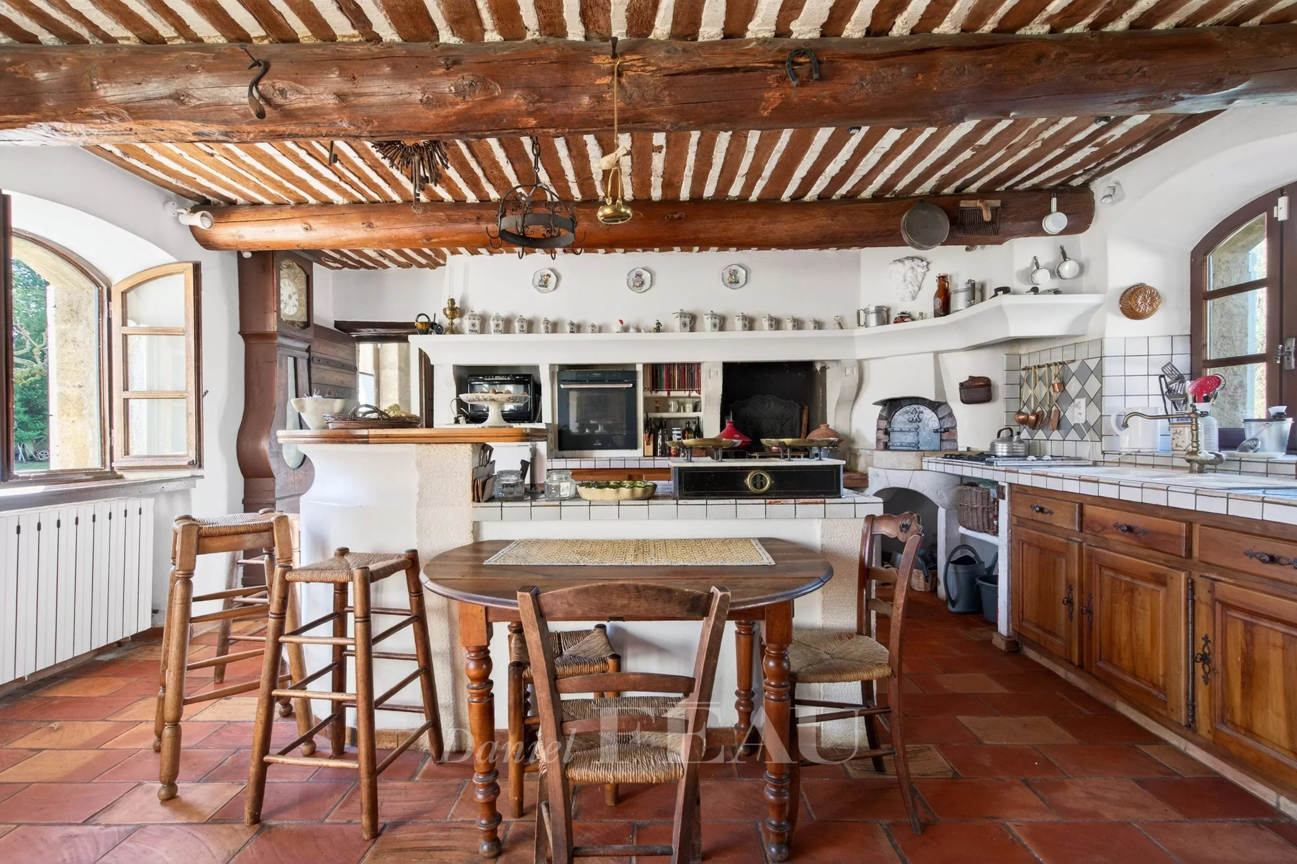Interior of a Provençal farmhouse with rustic kitchen, wooden table and exposed beams.