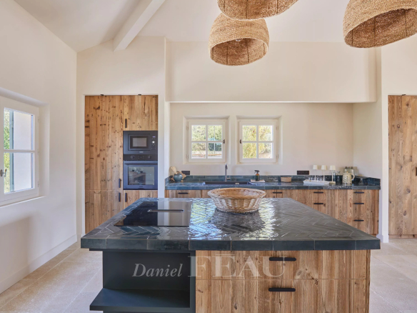 Modern kitchen with central island and wooden furniture in a renovated house in Paradou.