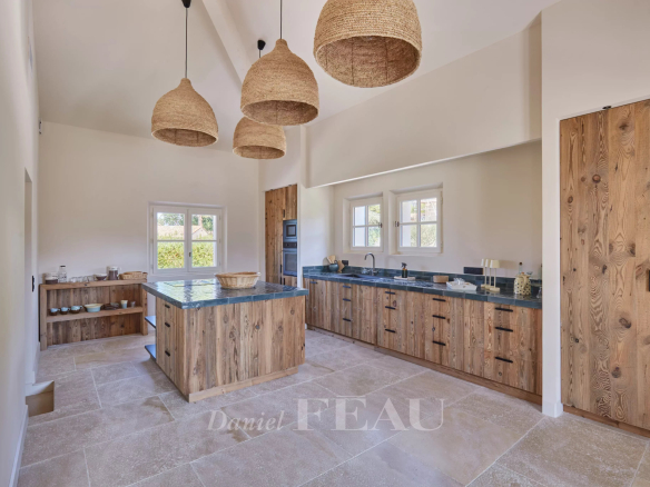 Modern kitchen with central island and wooden furniture in a renovated house in Paradou.