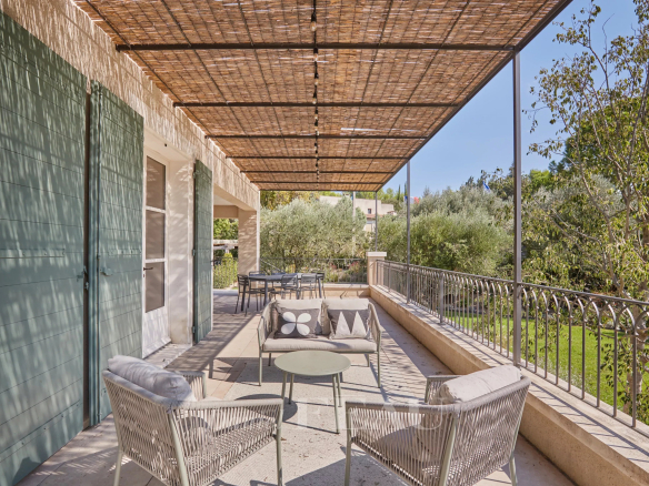 Terrace of a renovated house with outdoor furniture, overlooking a Mediterranean garden.