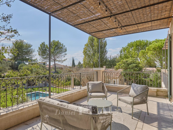 Terrace of a renovated house with outdoor furniture, overlooking a Mediterranean garden.