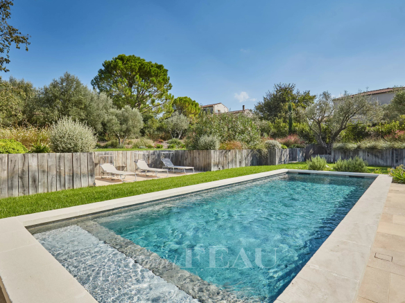 Swimming pool in a Mediterranean garden with sun loungers and plants.