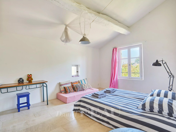 Chambre lumineuse avec lit à rayures et décoration simple dans un mas provençal.