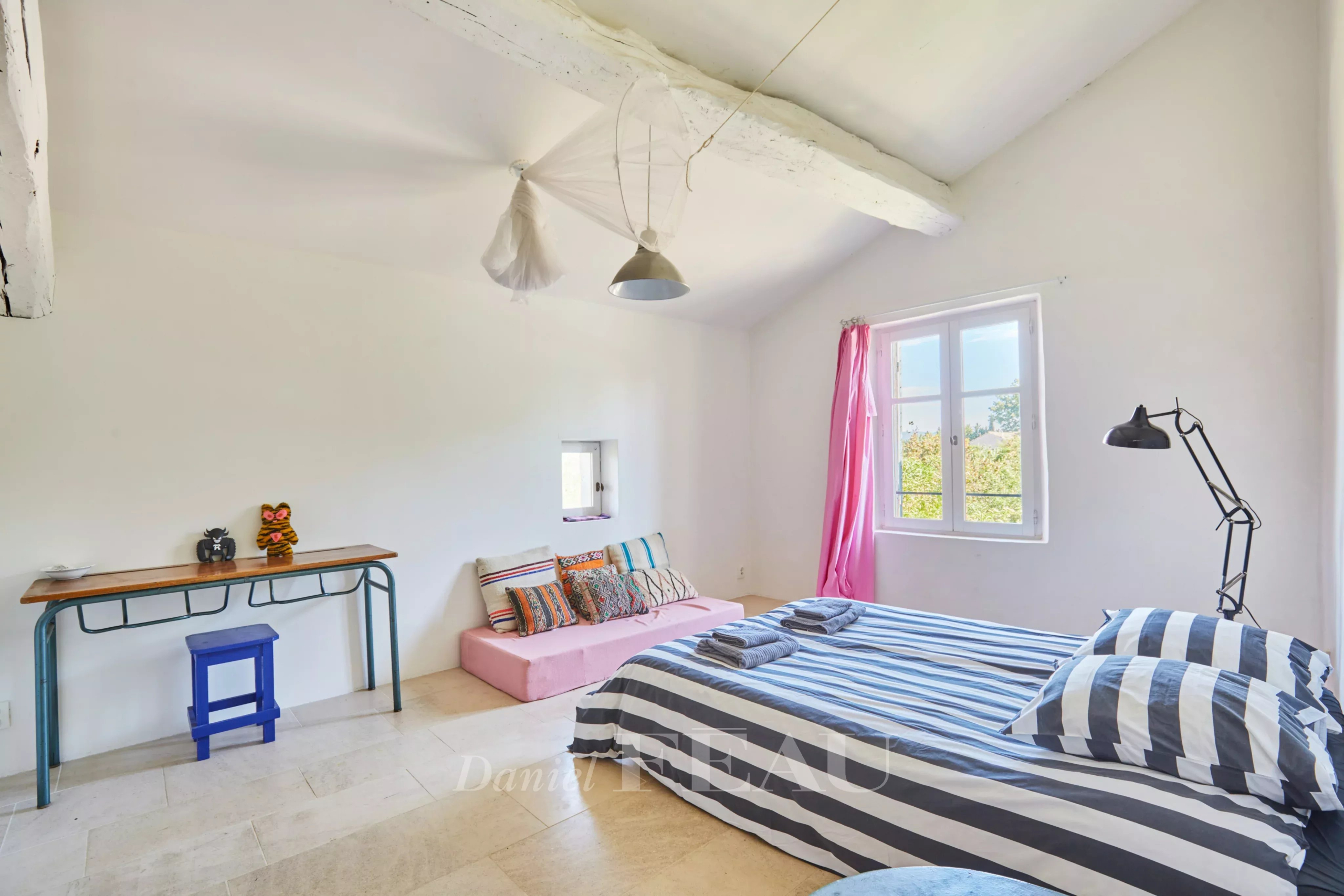 Chambre lumineuse avec lit à rayures et décoration simple dans un mas provençal.