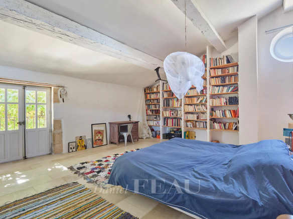 Chambre spacieuse avec bibliothèque et lit dans une ancienne ferme provençale.