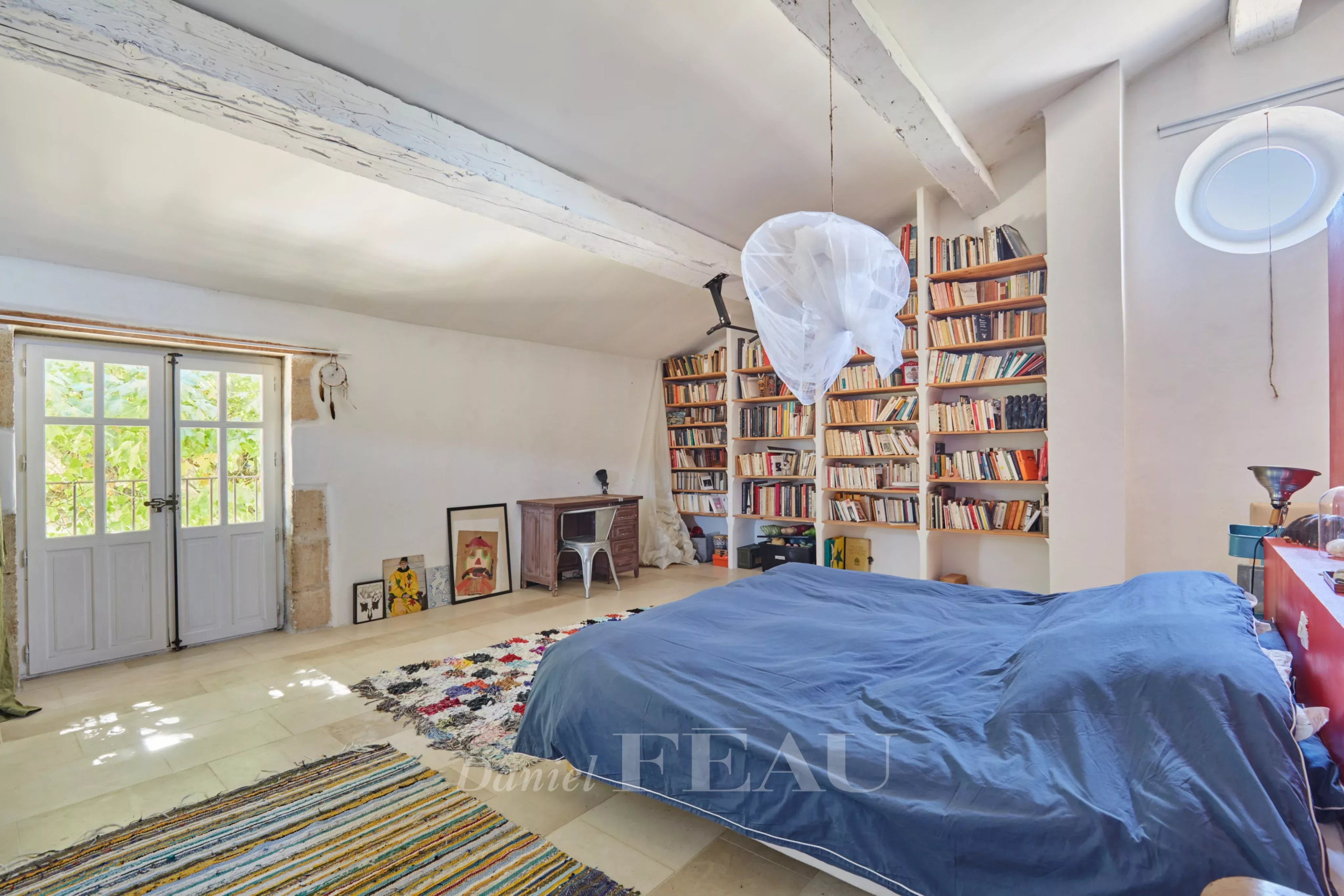 Chambre spacieuse avec bibliothèque et lit dans une ancienne ferme provençale.