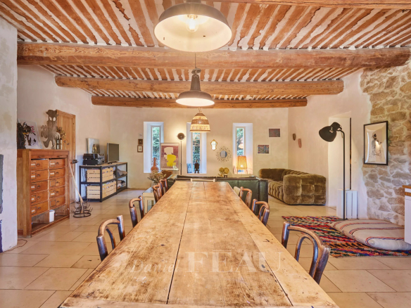 Intérieur d'un mas provençal avec poutres apparentes et grande table en bois