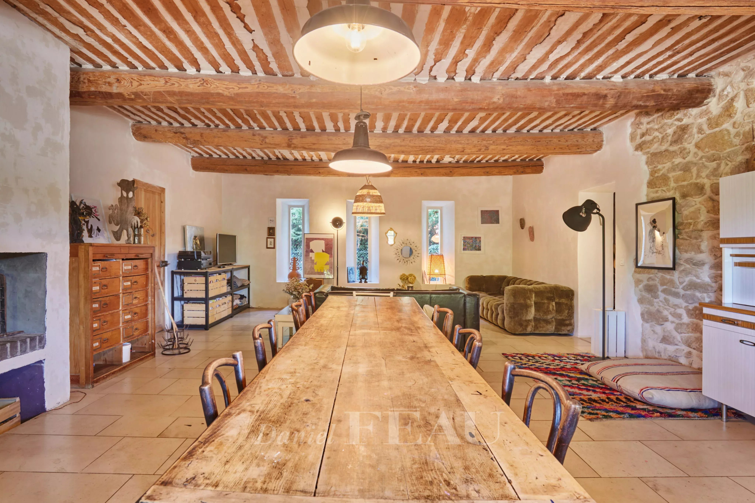 Intérieur d'un mas provençal avec poutres apparentes et grande table en bois