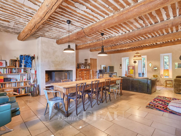 Intérieur d'un mas provençal avec poutres apparentes et mobilier convivial.