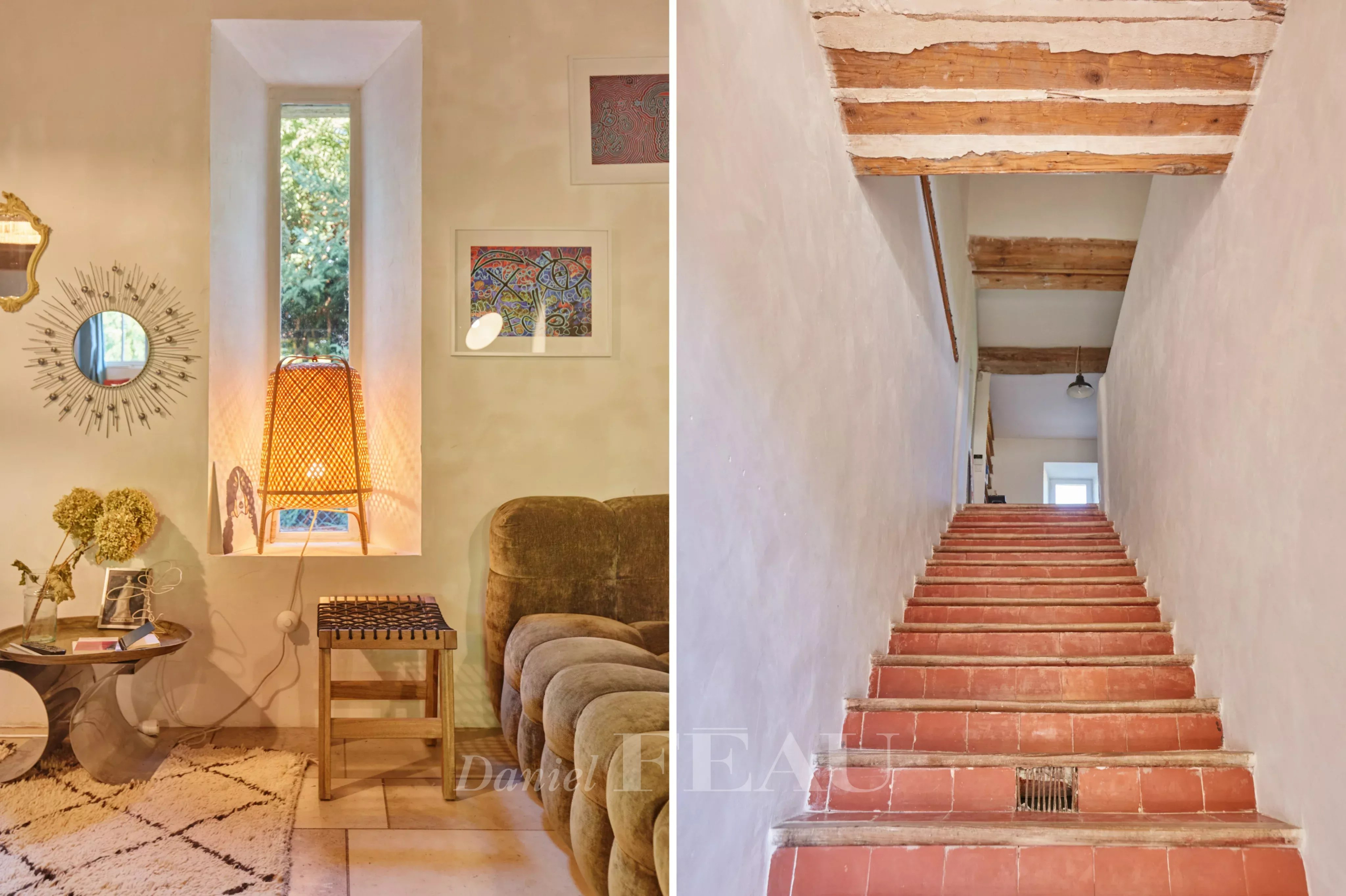 Intérieur d'un mas provençal avec un coin salon et un escalier en terre cuite.