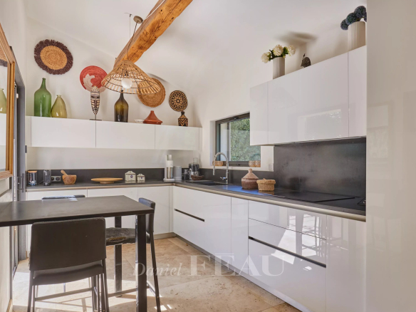 Cuisine moderne avec mobilier blanc et noir, éclairage design, et éléments décoratifs en Provence.
