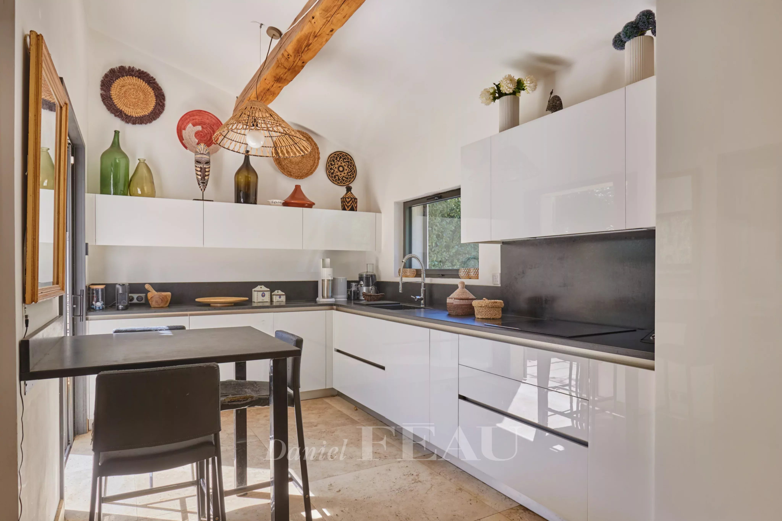 Cuisine moderne à Eygalières Cuisine moderne avec mobilier blanc et noir, éclairage design, et éléments décoratifs en Provence.