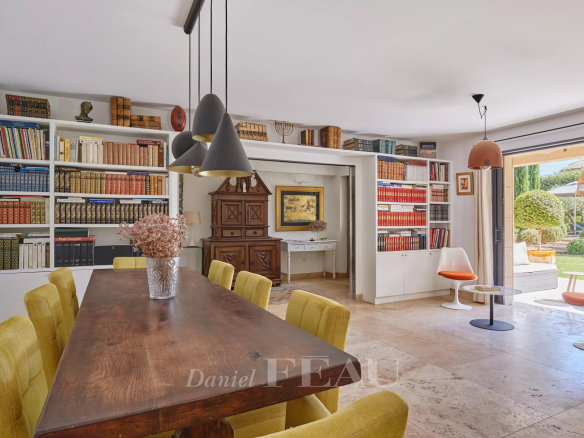 Intérieur d'une maison à Eygalières avec une salle à manger et des étagères remplies de livres.