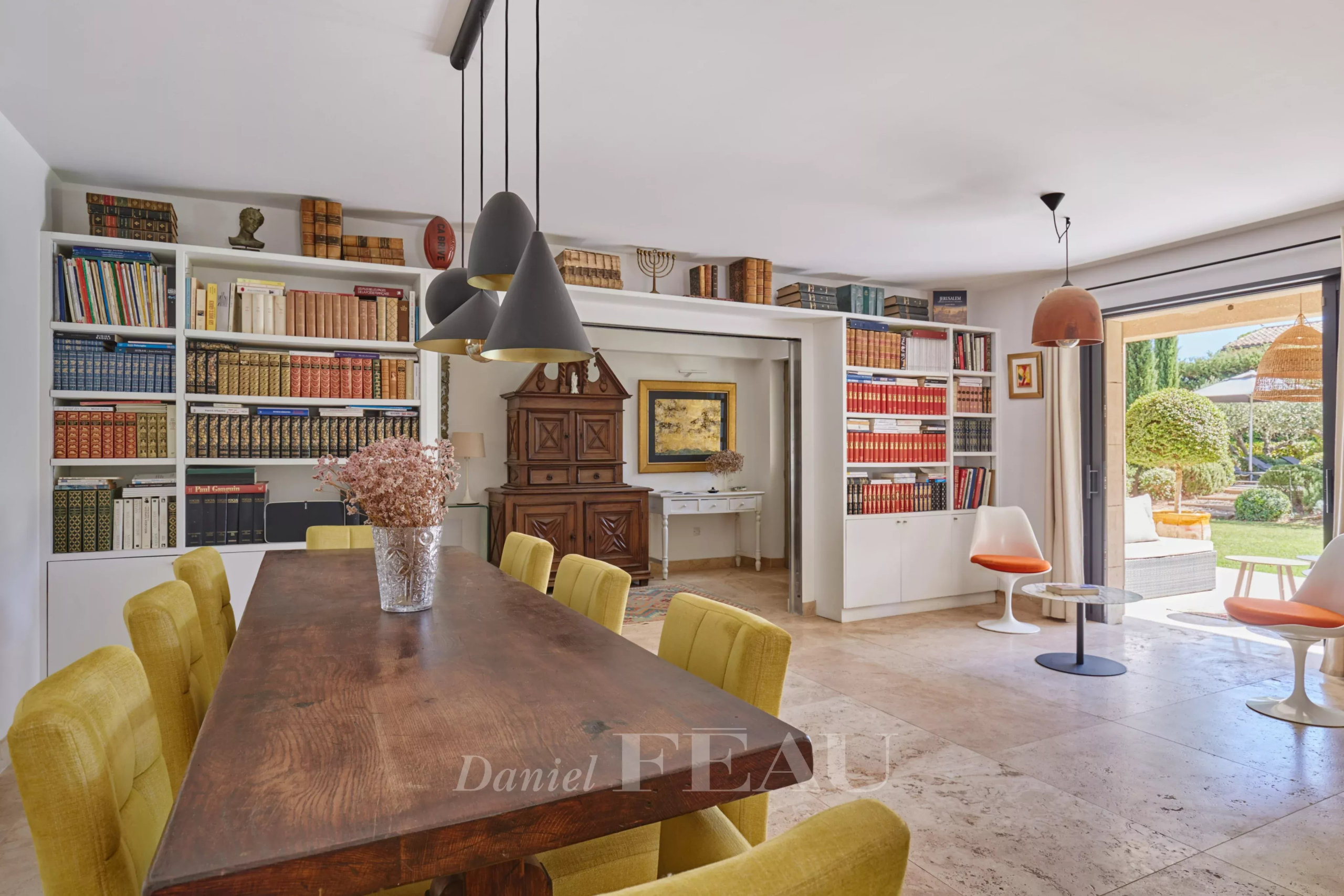 Salle à manger dans une maison à Eygalières Intérieur d'une maison à Eygalières avec une salle à manger et des étagères remplies de livres.
