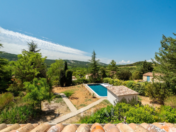 Vue panoramique sur une villa avec piscine et terrain paysager à Rustrel, entourée de verdure.